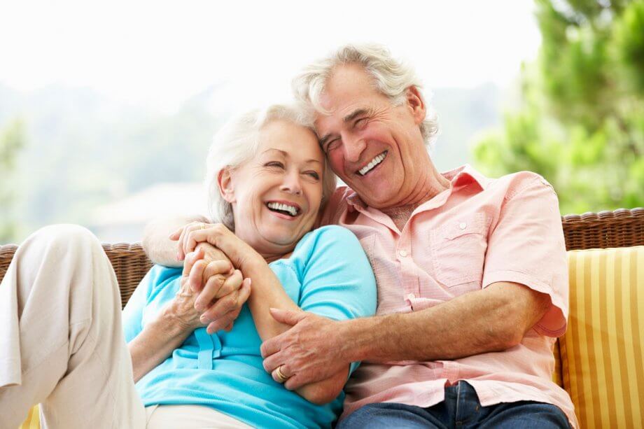 mature couple laughs on outdoor couch