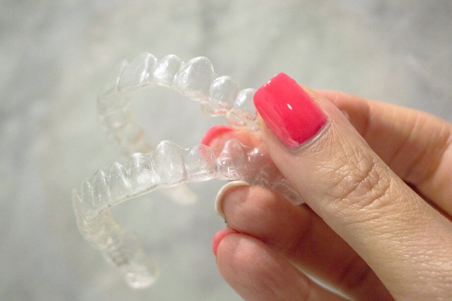 female hand holding Invisalign trays