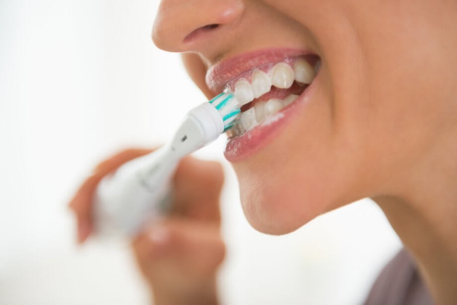 Closeup On Young Woman Brushing Teeth With Electronic Toothbrush