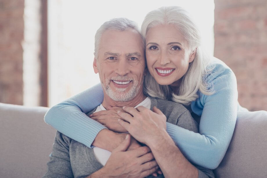 mature couple hugs and smiles on couch