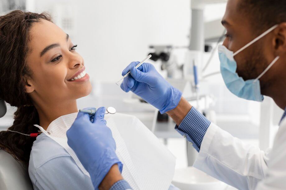 female patient in dental chair smiles at male dentist