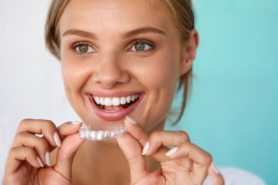 teen preparing to insert Invisalign tray into her mouth