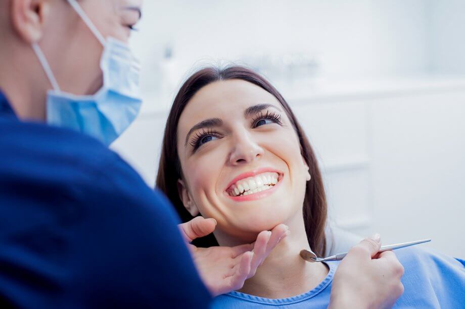 woman smiles up at dentist from dental chair